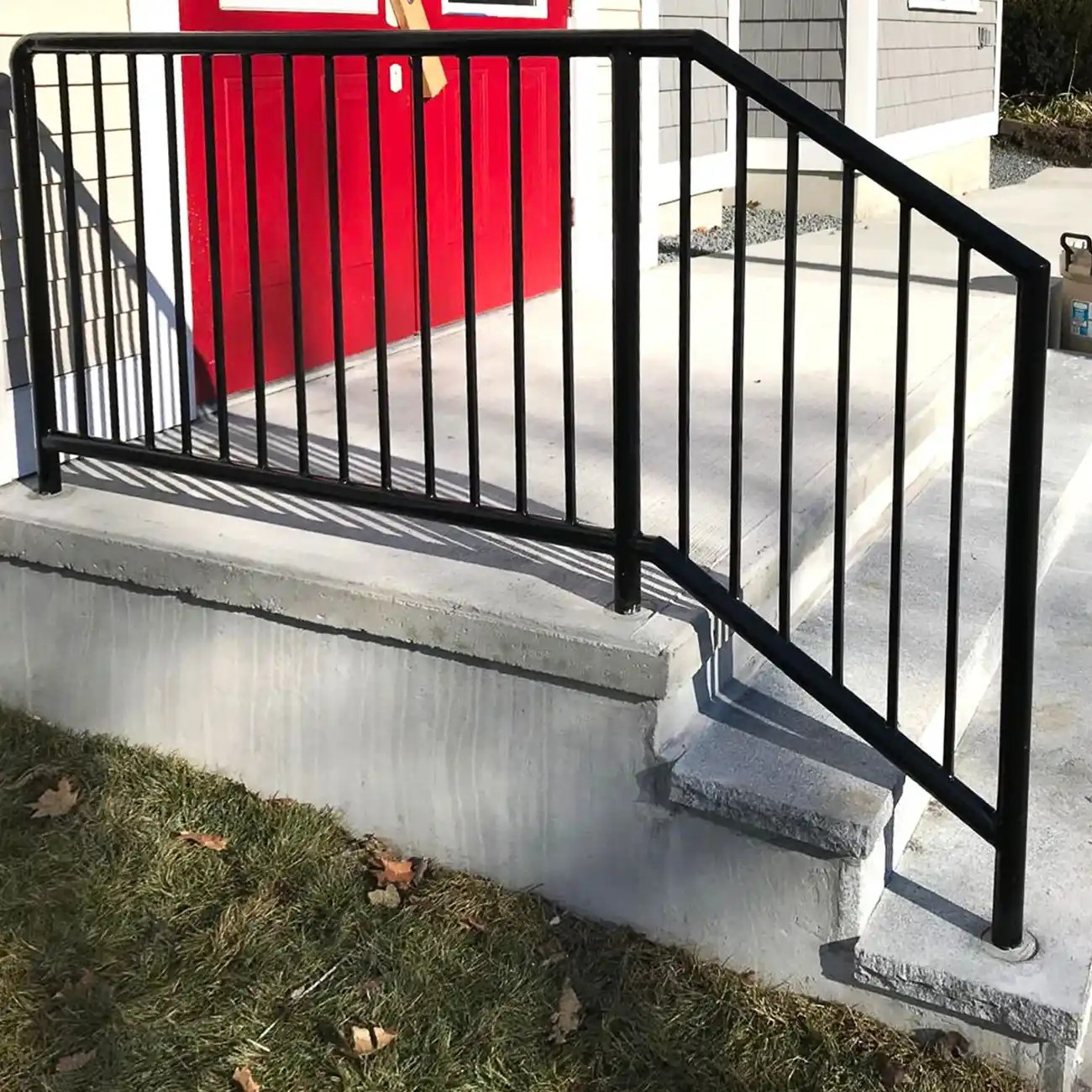 Black railing installed outside a building with red doors